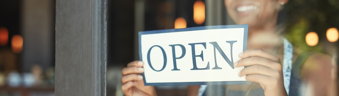 A small business owner with an "open" sign