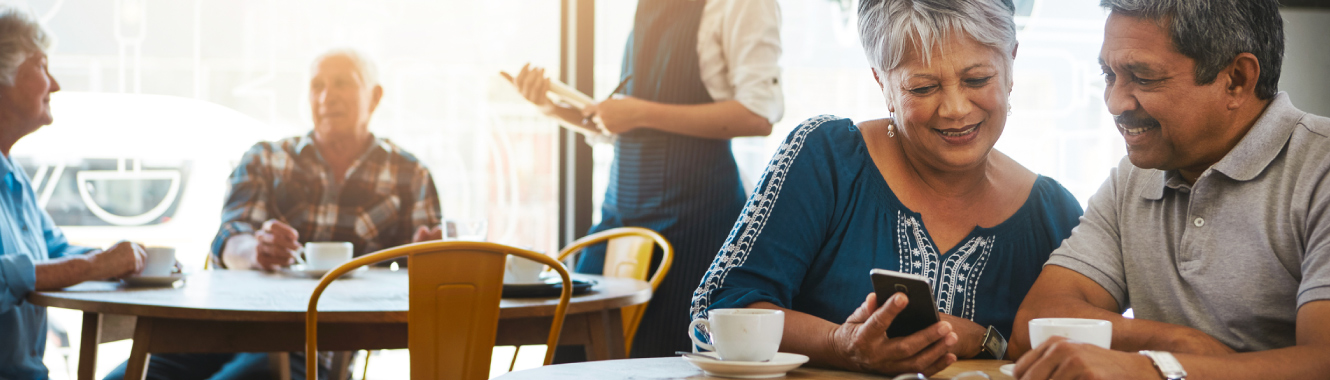 A mature couple in coffee shop using mobile phone