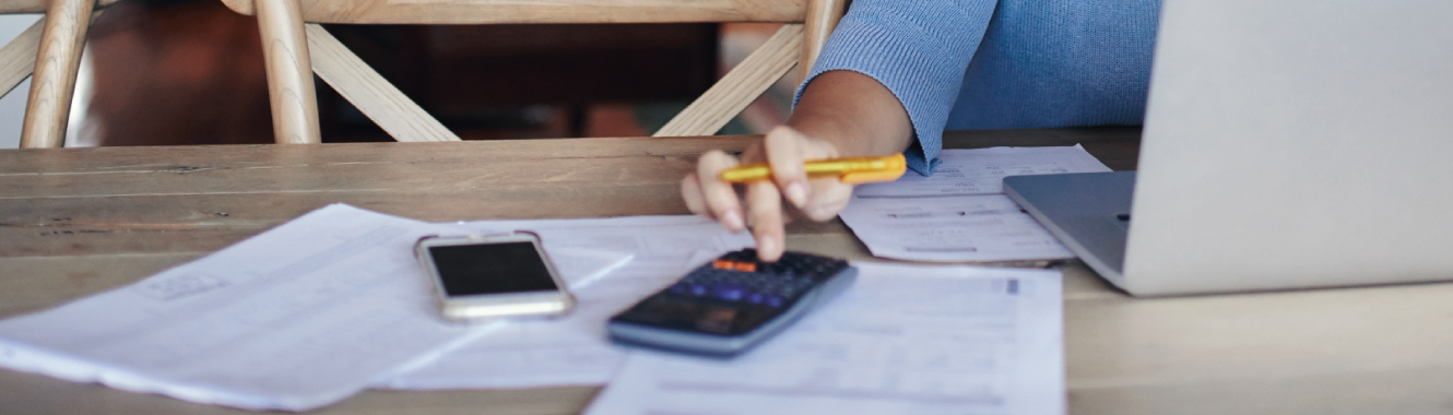 Person with a calculator in front of a laptop.