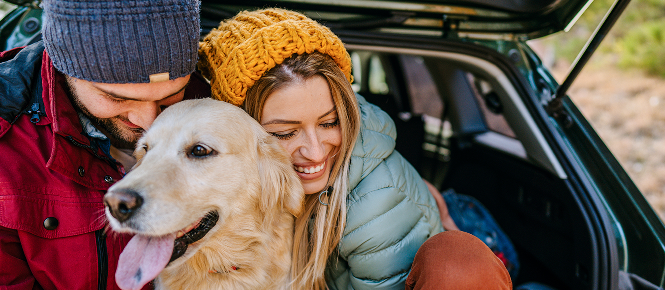Happy couple on a road trip with their dog.
