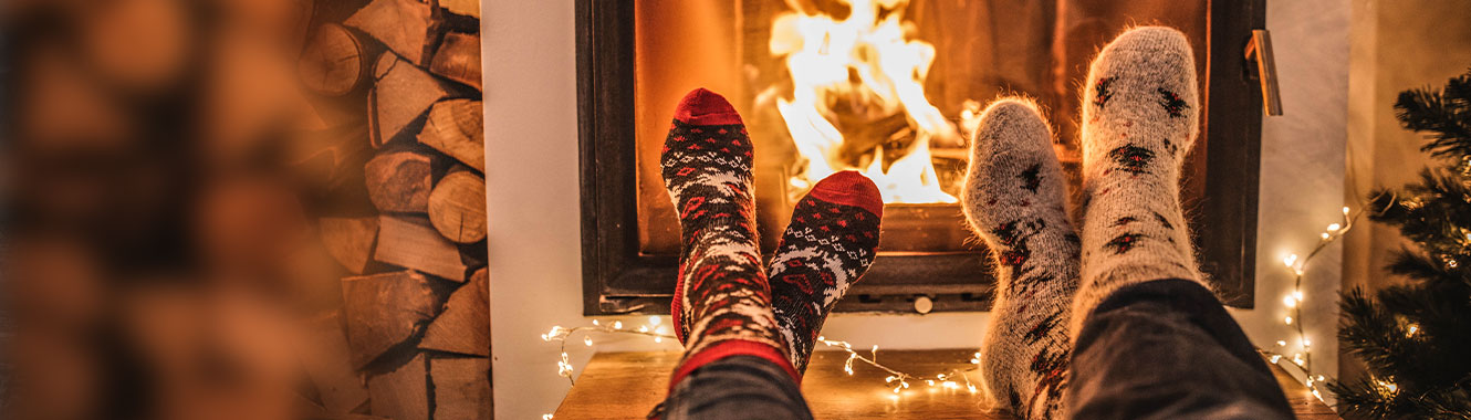 Couple warming their feet in front of the fireplace.