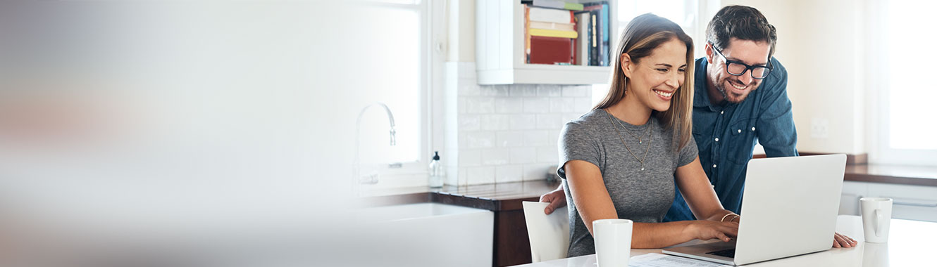 Couple smiling at laptop screen.