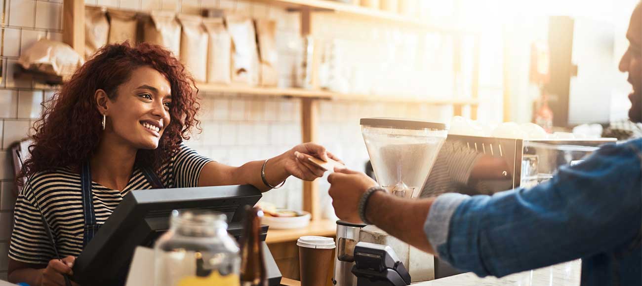A barista accepting a credit card payment from a customer in a cafe.